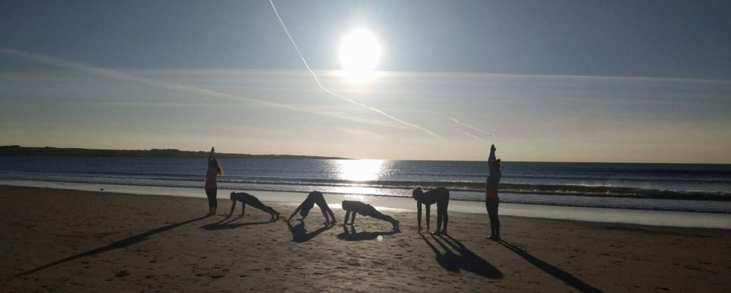 People on the beach practicing yoga