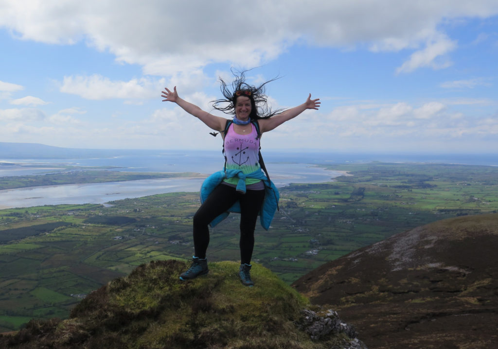 woman standing on the top of the mountain with an open arms