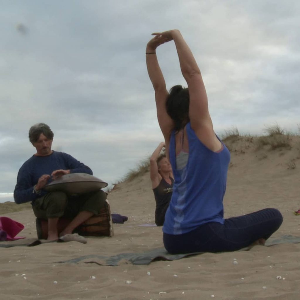 woman sitting on the sand exercising