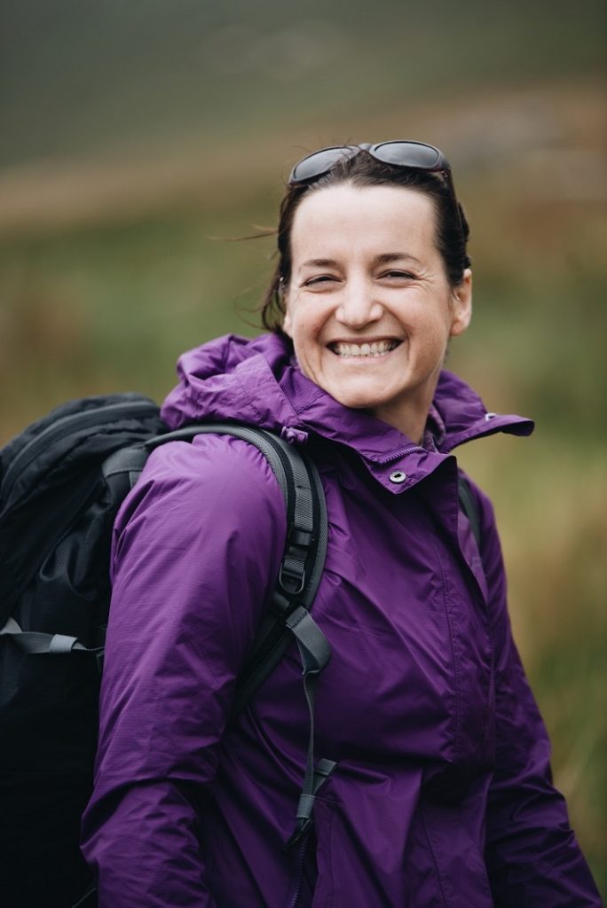 Woman is wearing purple jacket and smiling